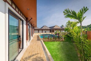 Ein modernes Haus mit Swimmingpool, überdachter Terrasse und gepflegtem Rasen.