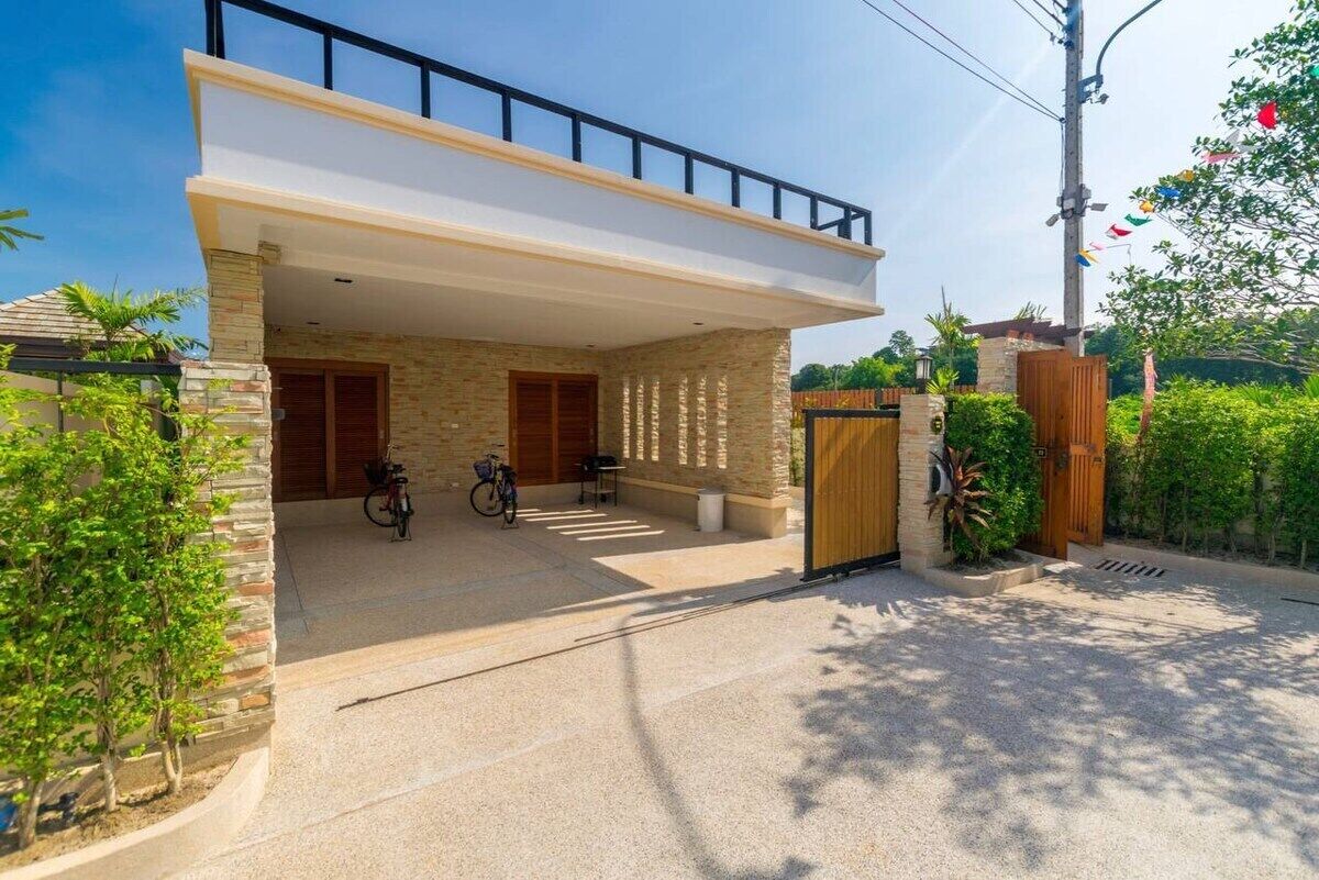 Une maison moderne dotée d’un patio couvert, d’une porte en bois et d’un vélo garé à l’extérieur.