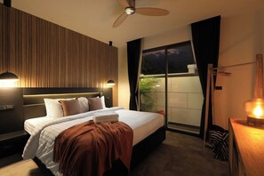 A modern hotel room with a bed, a ceiling fan, a nightstand, and a view of the outside. - Modern 4BR Villa with Pool | Rawai | Capital Pro (Rawai)