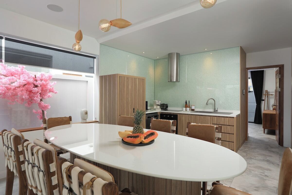 A modern kitchen with a central island, wooden cabinets, and a large window.