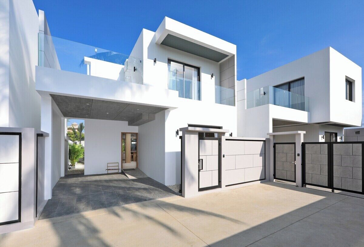 A modern two-story house with a covered driveway, large windows, and a gated entrance.