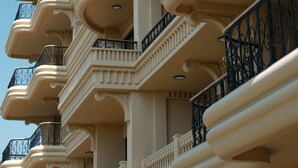 Um edifício de vários andares com varandas, cada uma adornada com grades ornamentadas e um desenho circular.