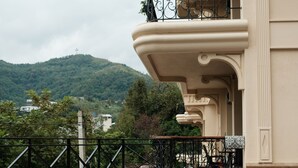 Uma área de piscina com vista para uma montanha, uma varanda com grade e mobiliário de exterior.