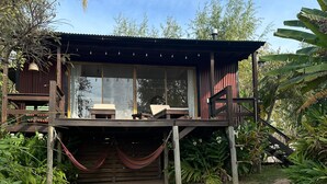Una cabaña de madera con un porche, ventanas amplias y una hamaca.