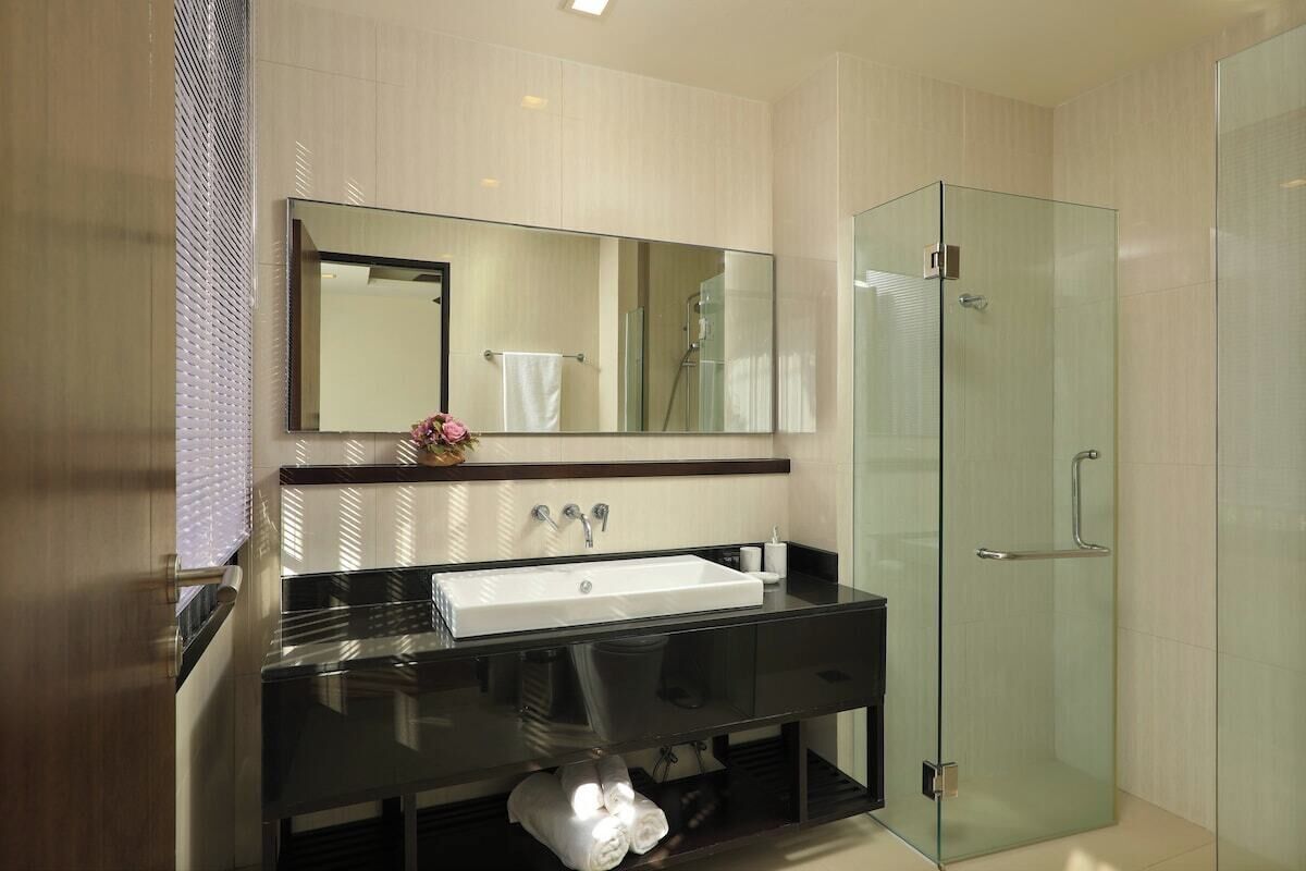 Un bany modern amb un mirall gran, un lavabo i una cabina de dutxa de vidre.