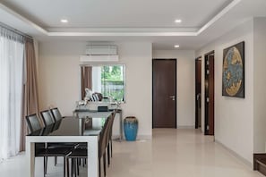 Un comedor moderno con una mesa, sillas, un jarrón grande y una puerta que da a otra habitación.