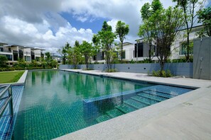 Una piscina rectangular con agua azul cristalina, rodeada por un deck de concreto y un muro bajo.