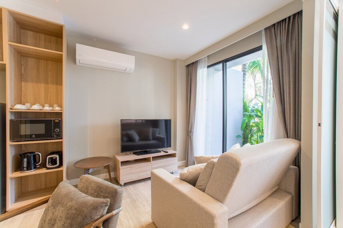 A modern living room with a sofa, a TV, a coffee maker, and a shelf with kitchen items.