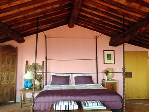 A room with a four-poster bed, a wooden ceiling, a pink wall, and a wooden door. - Apartment in farmhouse, nestled in olive grove, 15 minutes from Lucca (Capannori)