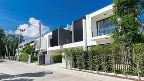 Une rue résidentielle moderne, bordée de maisons contemporaines, avec un ciel dégagé et un trottoir.