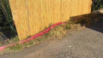 Un'alta staccionata di bambù con un tubo rosso che corre lungo la base.