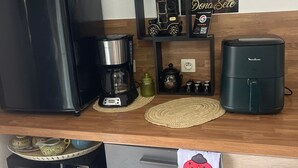 Et køkken med et sort køleskab, kaffemaskine, mikrobølgeovn, brødrister og et mindre køleskab.