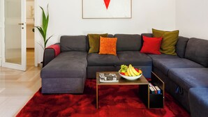A modern living room with a sectional sofa, a red rug, a coffee table with fruit, and a pendant light. - Artistic Oasis in Vatican (Roma)
