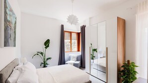 A modern bedroom with a bed, bedside table, lamp, and a large mirror. - Artistic Oasis in Vatican (Roma)
