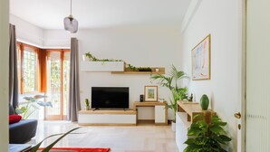 A modern living room with a flat-screen TV, a wooden desk, a red rug, and a large plant. - Artistic Oasis in Vatican (Roma)