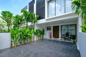 A modern two-story building with a flat roof, large windows, and a paved courtyard. - 3BR Townhouse Near Bangtao Beach | Capital Pro (Tambon Choeng Thale)