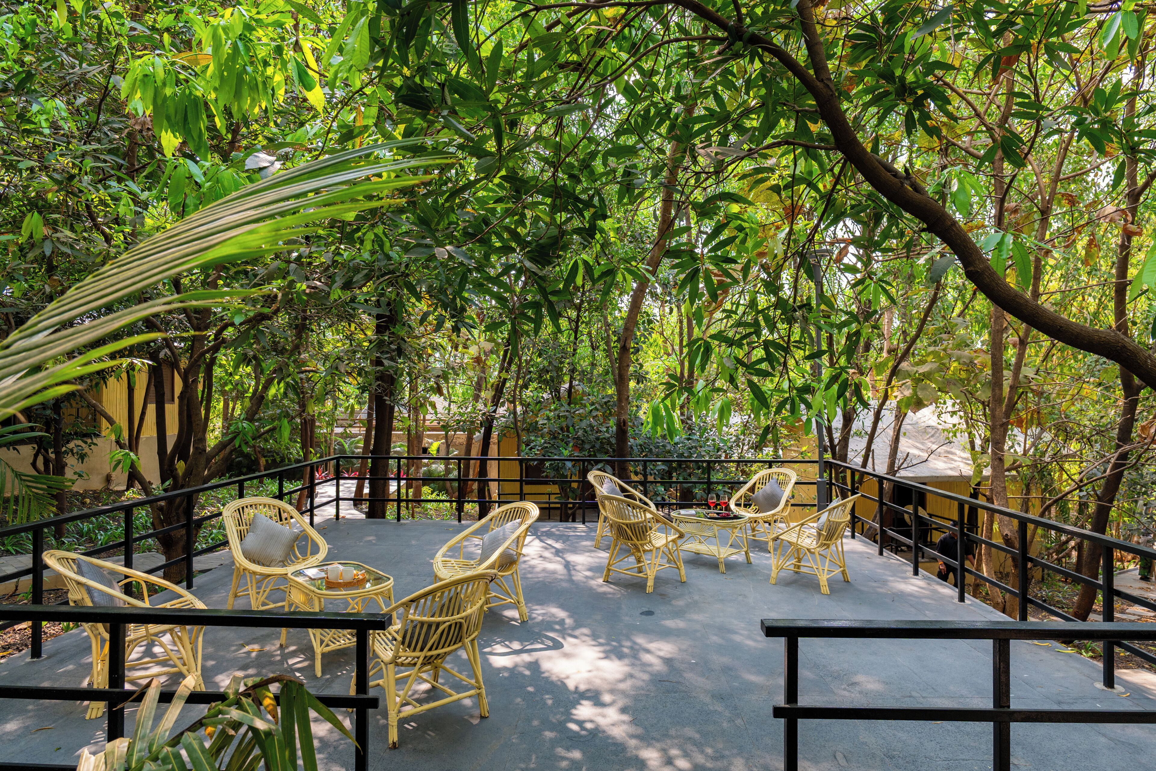A terrace with wicker furniture, surrounded by lush greenery.