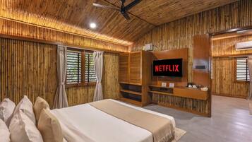 Una habitación con una cama, un televisor montado en una pared de madera y un ventilador de techo.