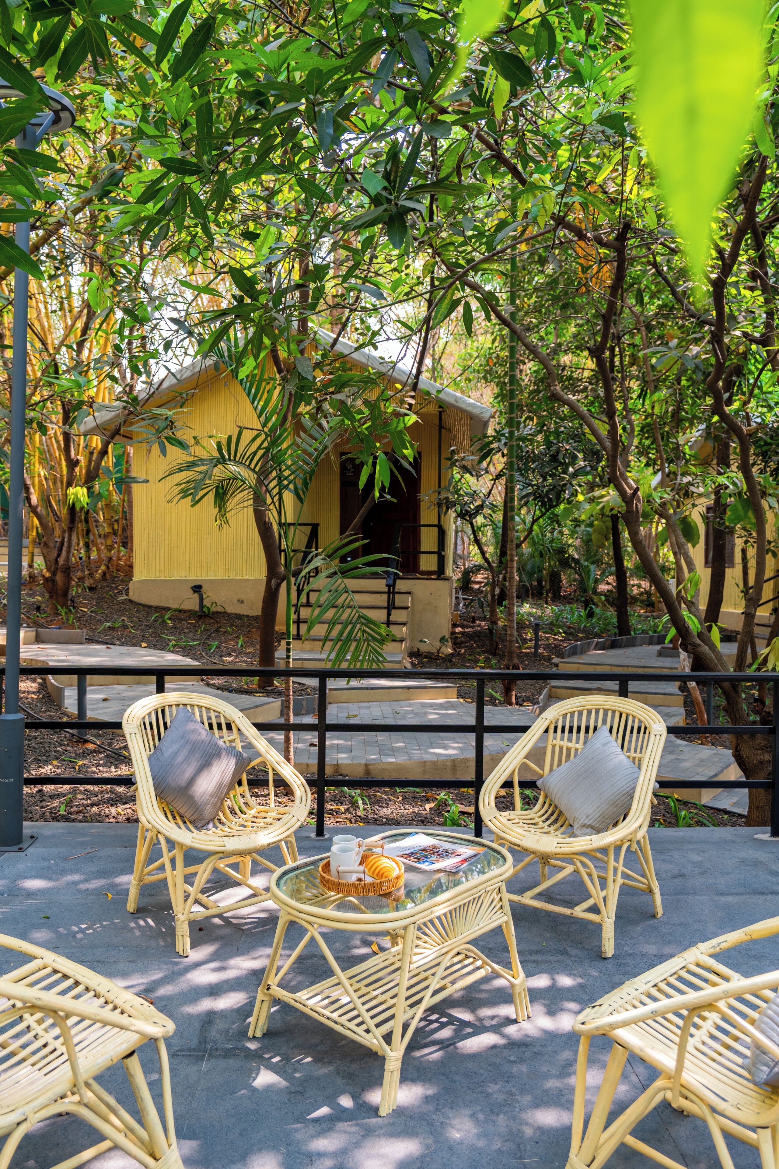 Un patio con mobili in vimini, un tavolino e un edificio giallo sullo sfondo.
