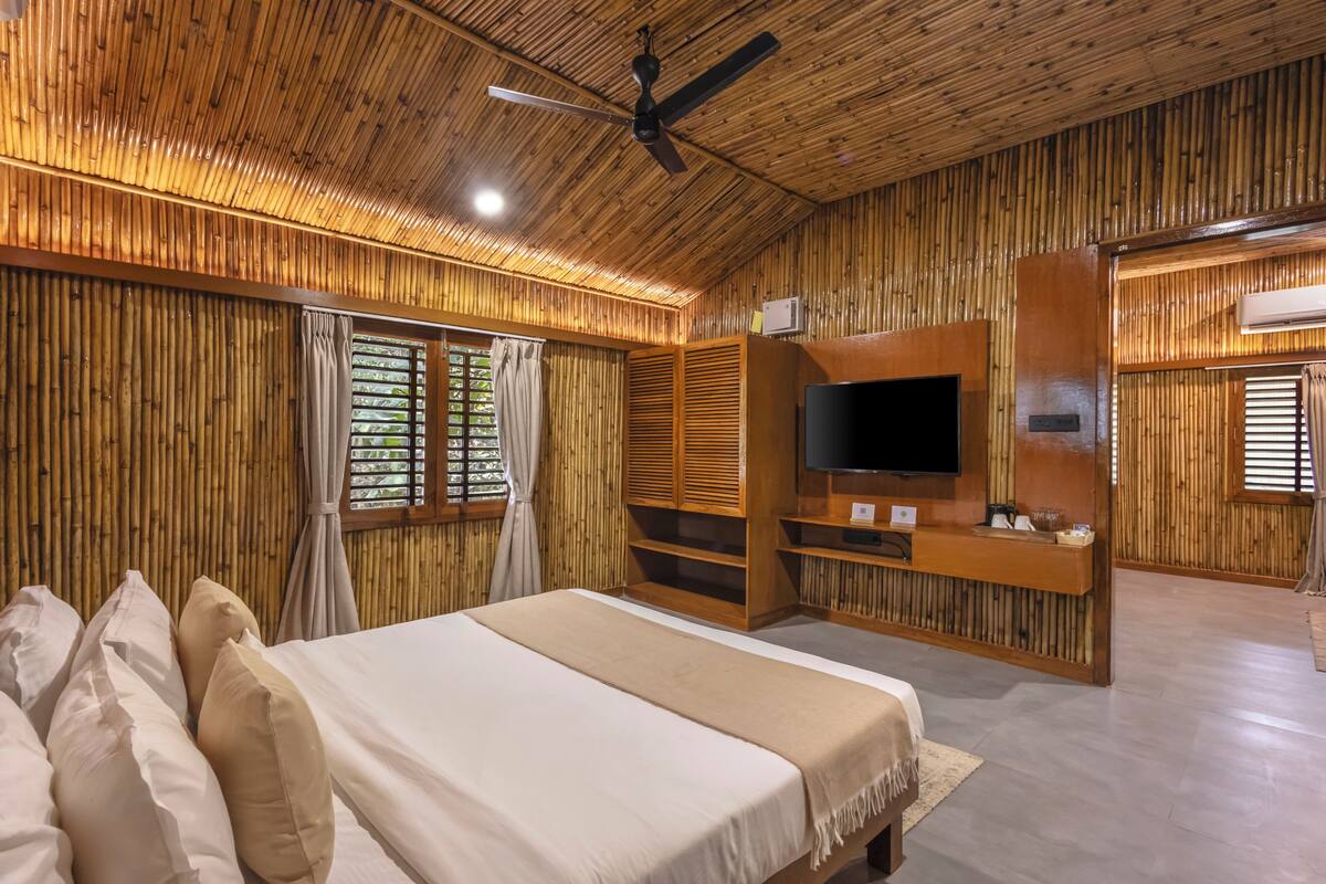 A room with a bed, a TV, and a ceiling fan.