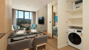 Ein modernes Hotelzimmer mit Essbereich, Fernseher, Waschmaschine und Blick ins Freie.