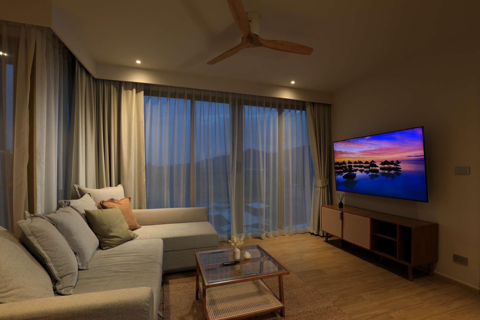 Ein Wohnzimmer mit Sofa, Couchtisch, Fernseher und Deckenventilator.