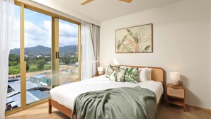 Ein Schlafzimmer mit einem großen Bett, einem Deckenventilator, Blick ins Freie und einem Gemälde an der Wand.