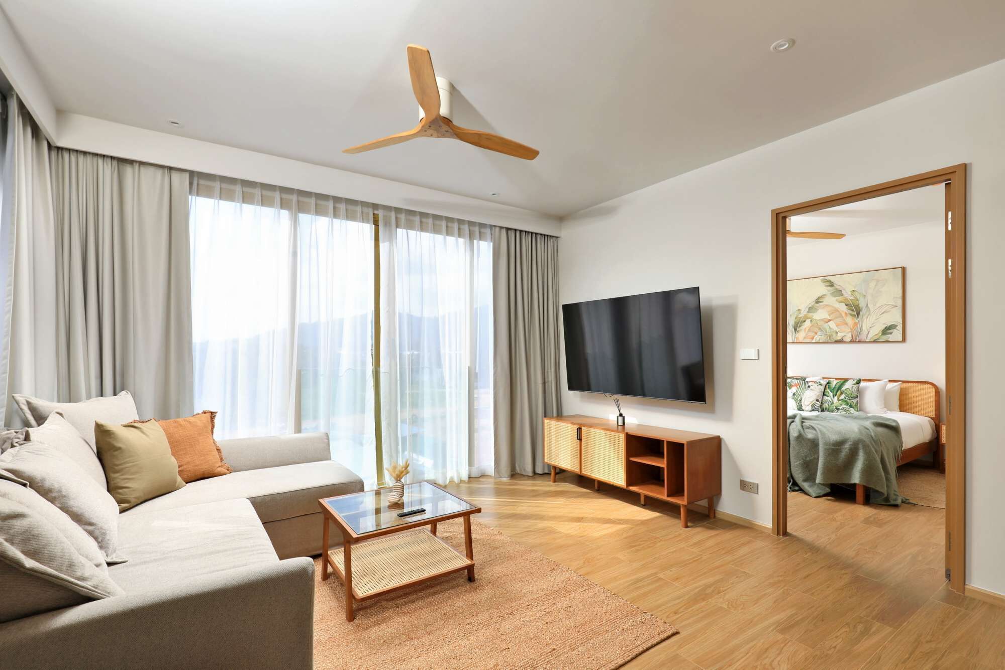Una sala de estar moderna con sofá, mesa de centro, televisor y ventilador de techo.