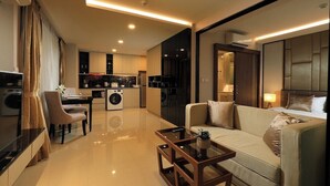 Una habitación de hotel moderna con sofá, mesa de centro, zona de comedor y cocina.