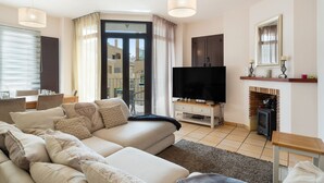 Un salon moderne avec un canapé, un téléviseur, une cheminée et une vue sur l’extérieur.