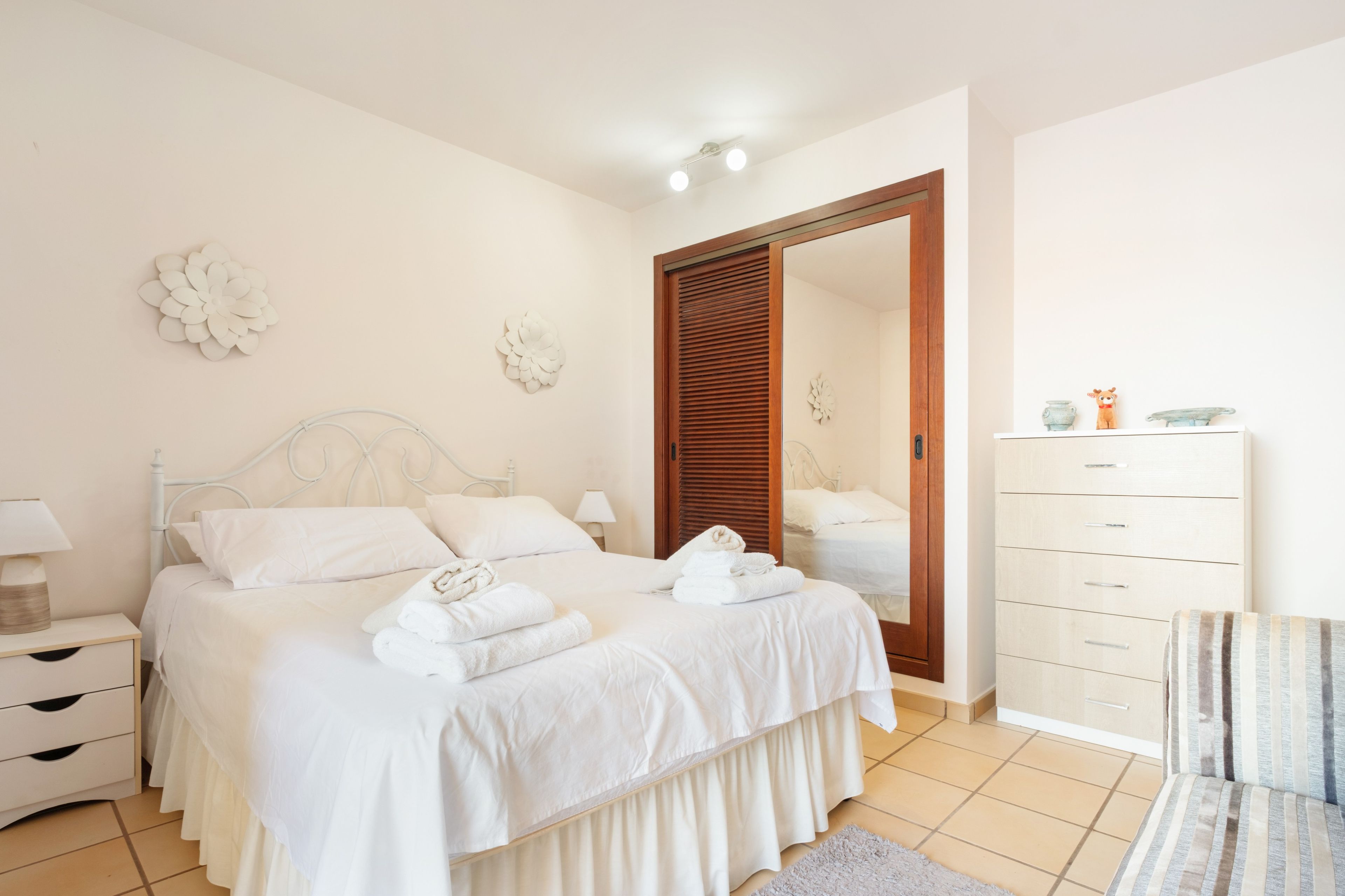 Een slaapkamer met een bed, nachtkastjes, een kledingkast en decoratieve muurdecoratie.