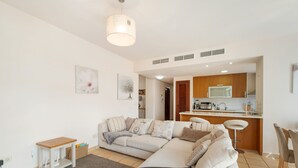 Un salon moderne avec un canapé, une petite table et un coin cuisine à l’arrière-plan.