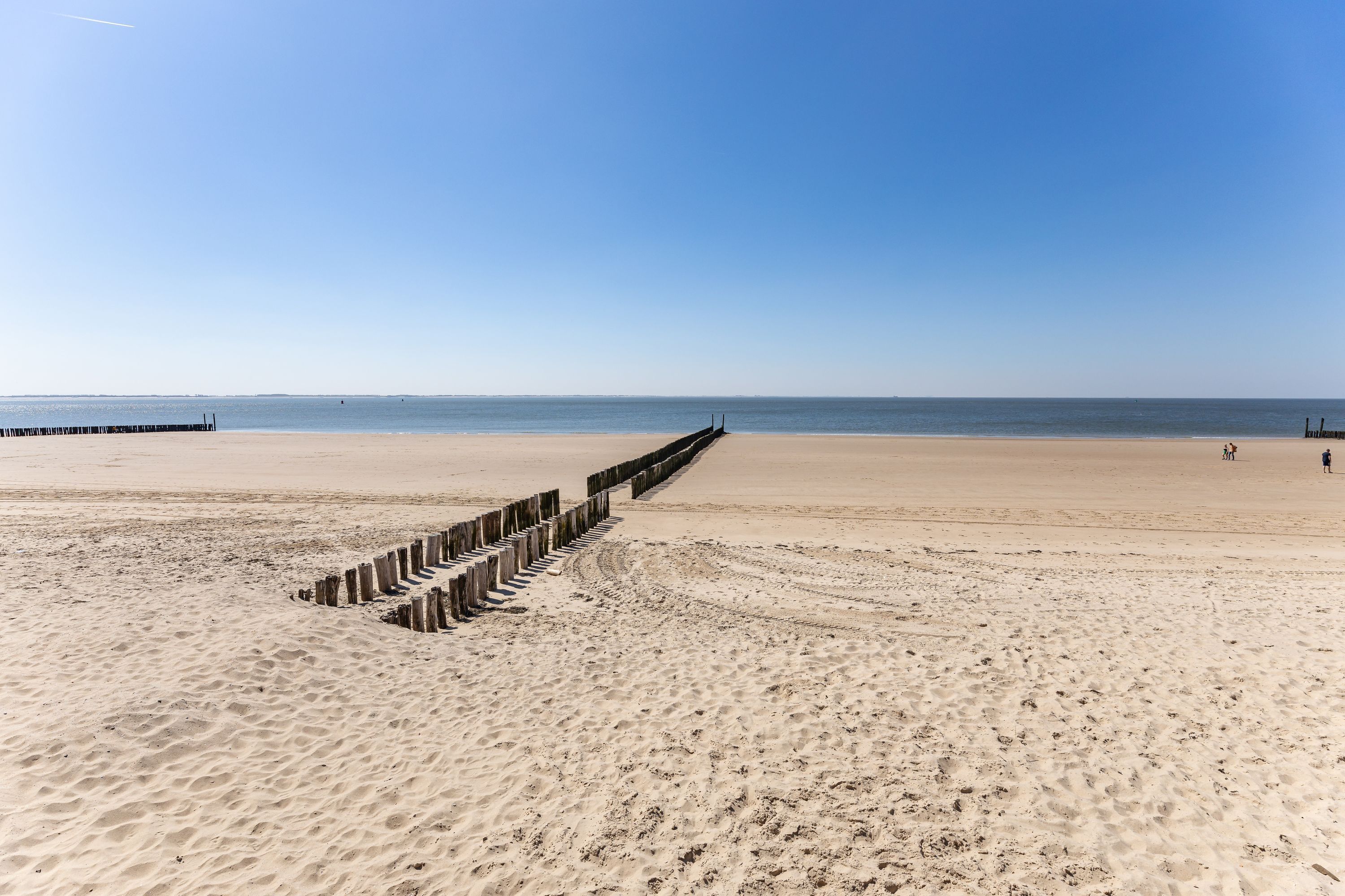 A sandy beach with a wooden jetty extending into the water.