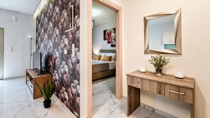 A modern hotel room with a large mirror, a wooden console, a potted plant, and a view into the bedroom. - Seaside Apartment 1 by Cretanhouses (Hersonissos)