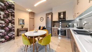 A modern kitchen with a central island, a dining area with yellow chairs, and a stone-patterned wall. - Seaside Apartment 1 by Cretanhouses (Hersonissos)