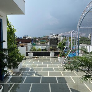 A rooftop terrace with potted plants, a metal structure, and a view of the cityscape. - AvyAm Blue Terrace Apartment in New Delhi! Room-2 (Superior) (New Delhi)