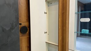 Un angolo di stanza con una porta in legno, un armadietto bianco e una vetrina.