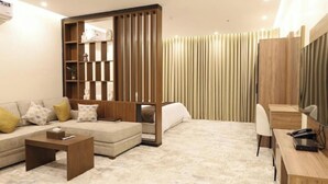 A modern living room with a sofa, coffee table, and a desk area. - Hadaj Town Apartment Hotel (Al-'Ula)