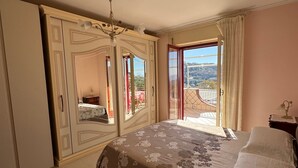 Ein Schlafzimmer mit einem Bett, einem Kleiderschrank, einem Spiegel und einem Balkon mit Aussicht.