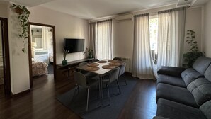 Ein modernes Wohnzimmer mit Essbereich, einer Couch, einem Fernseher und einer Pflanze.
