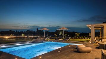 Una piscina con vistas al paisaje, mobiliario exterior y una zona cubierta.