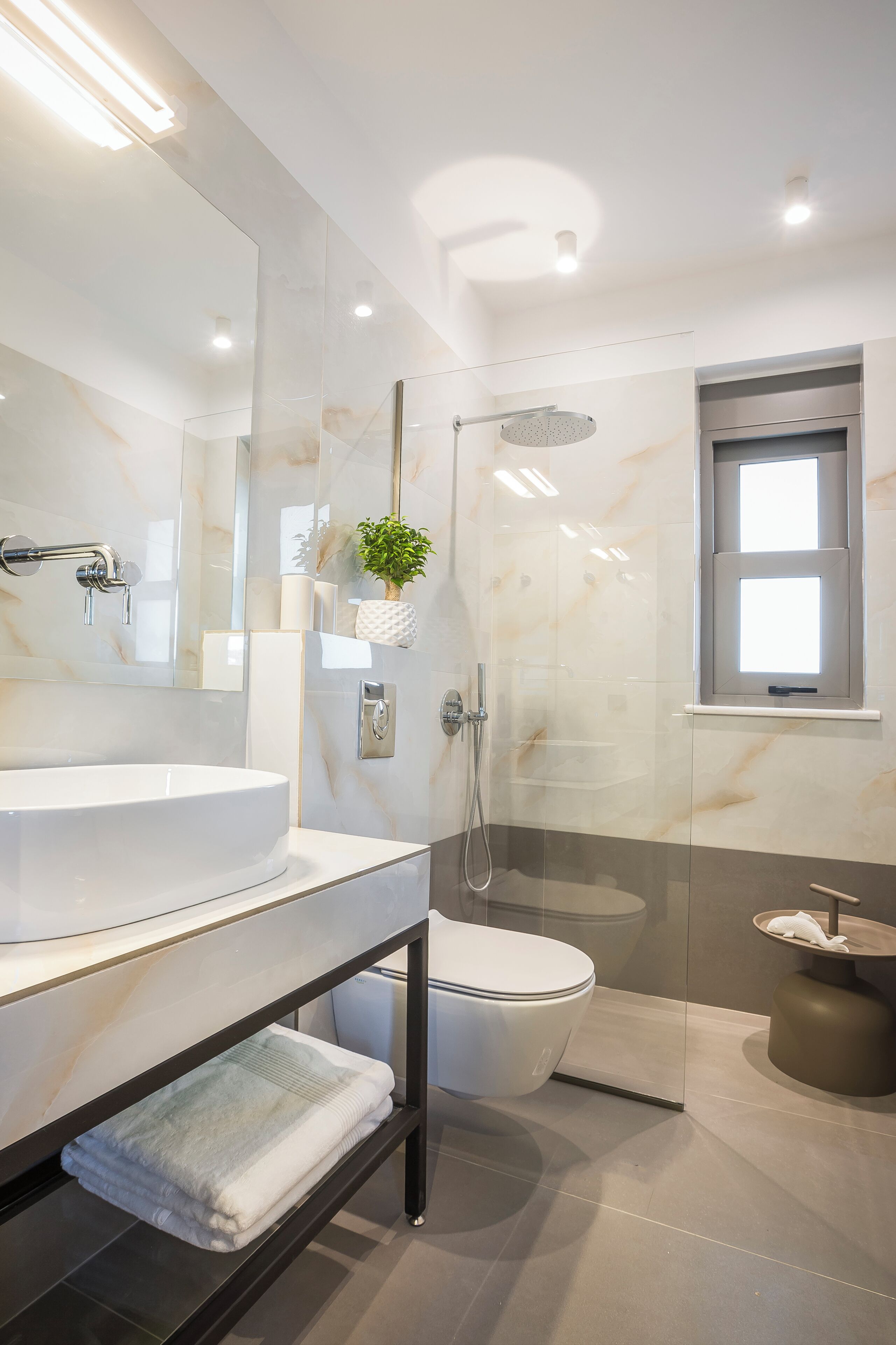 A modern bathroom with a glass-enclosed shower, a white sink, and a toilet.