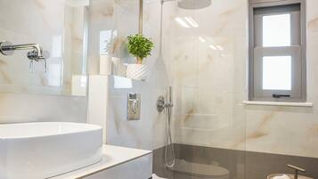 A modern bathroom with a glass-enclosed shower, a white sink, and a toilet.