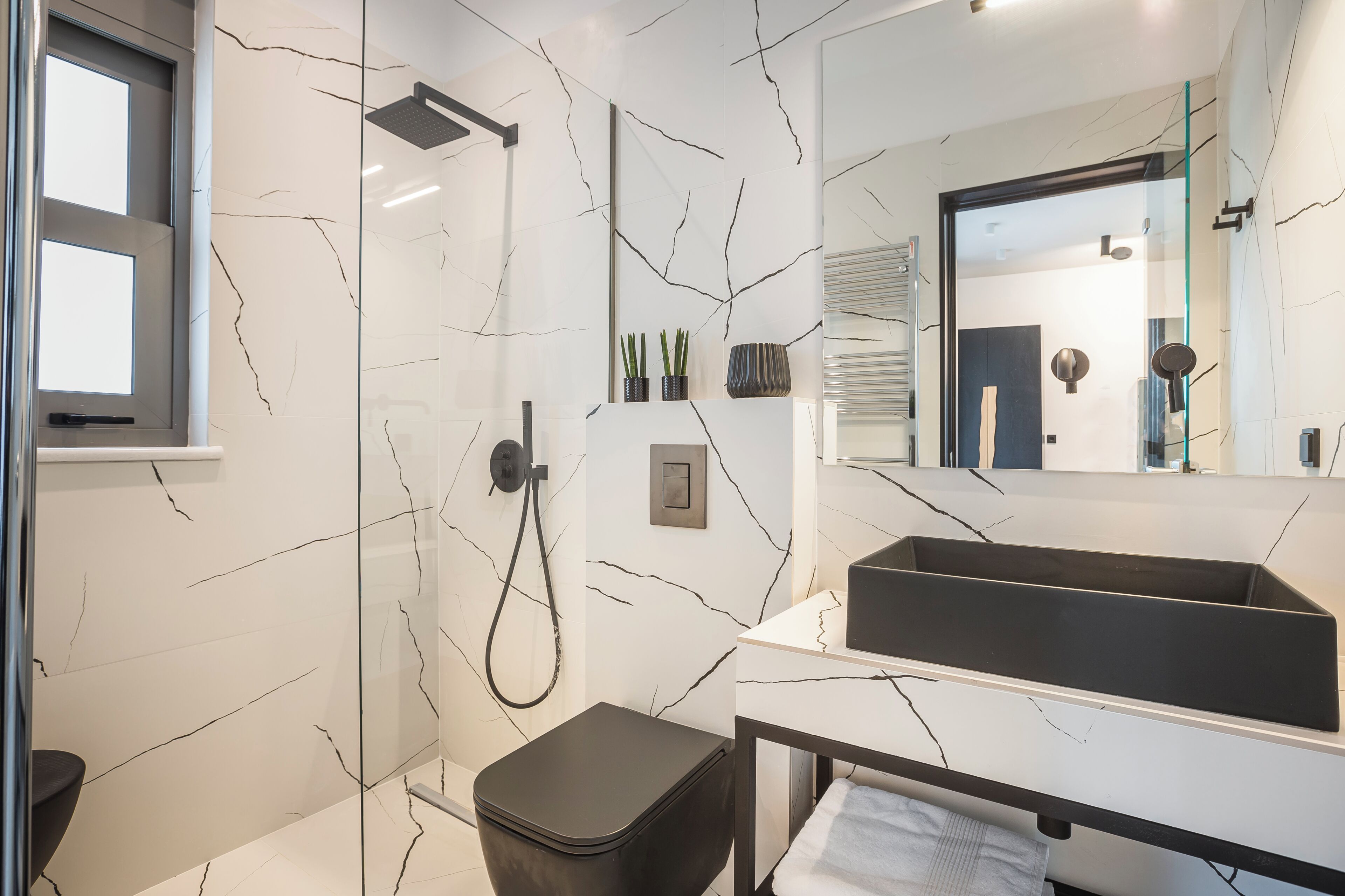 A modern bathroom with a glass shower enclosure, a black toilet, and a vanity with a mirror.