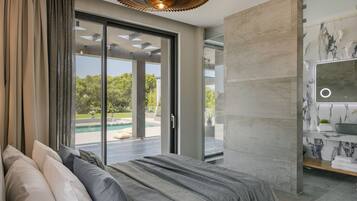 A modern bedroom with a large bed, a sliding glass door to a pool, and a bathroom with a marble backsplash.