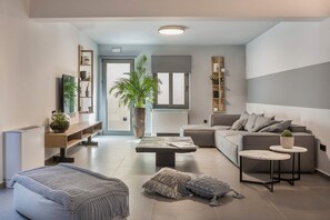 Een moderne woonkamer met een bank, salontafel en een grote potplant.