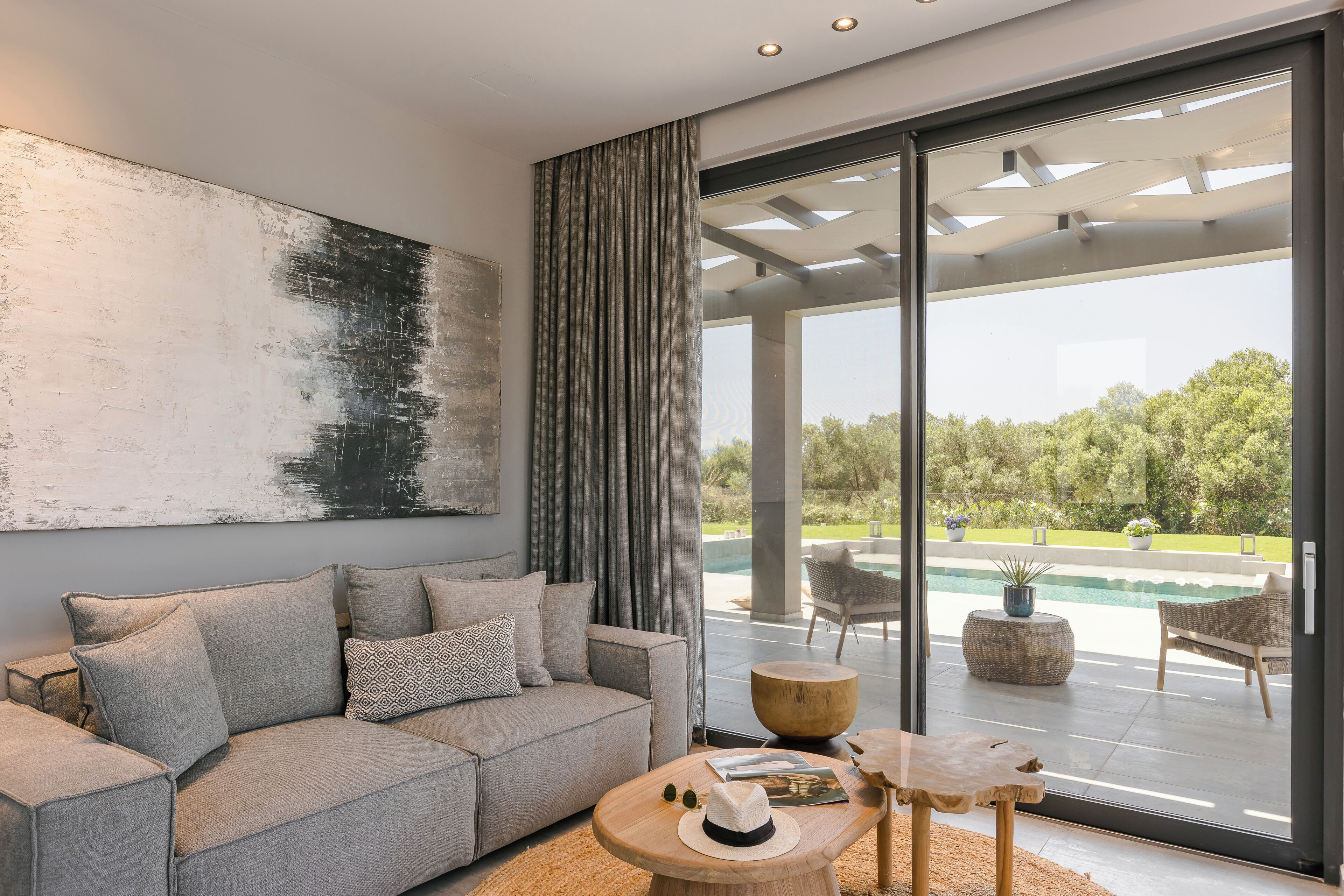 A modern living room with a grey sofa, a coffee table, and a large abstract painting.