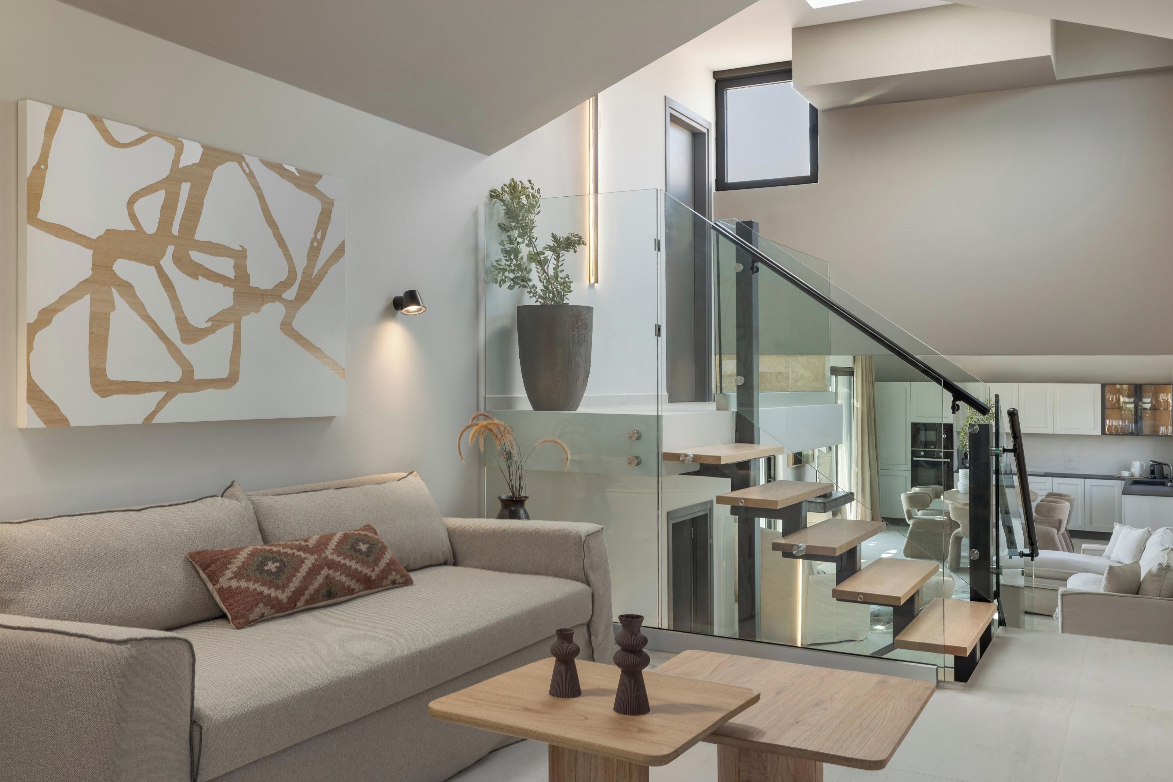 Un espai de vida modern amb un sofà, taula de centre i una escala que condueix a un nivell superior.