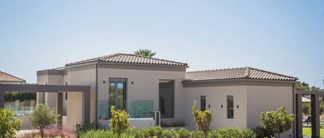 A modern two-story house with a flat roof, large windows, and a well-maintained garden.