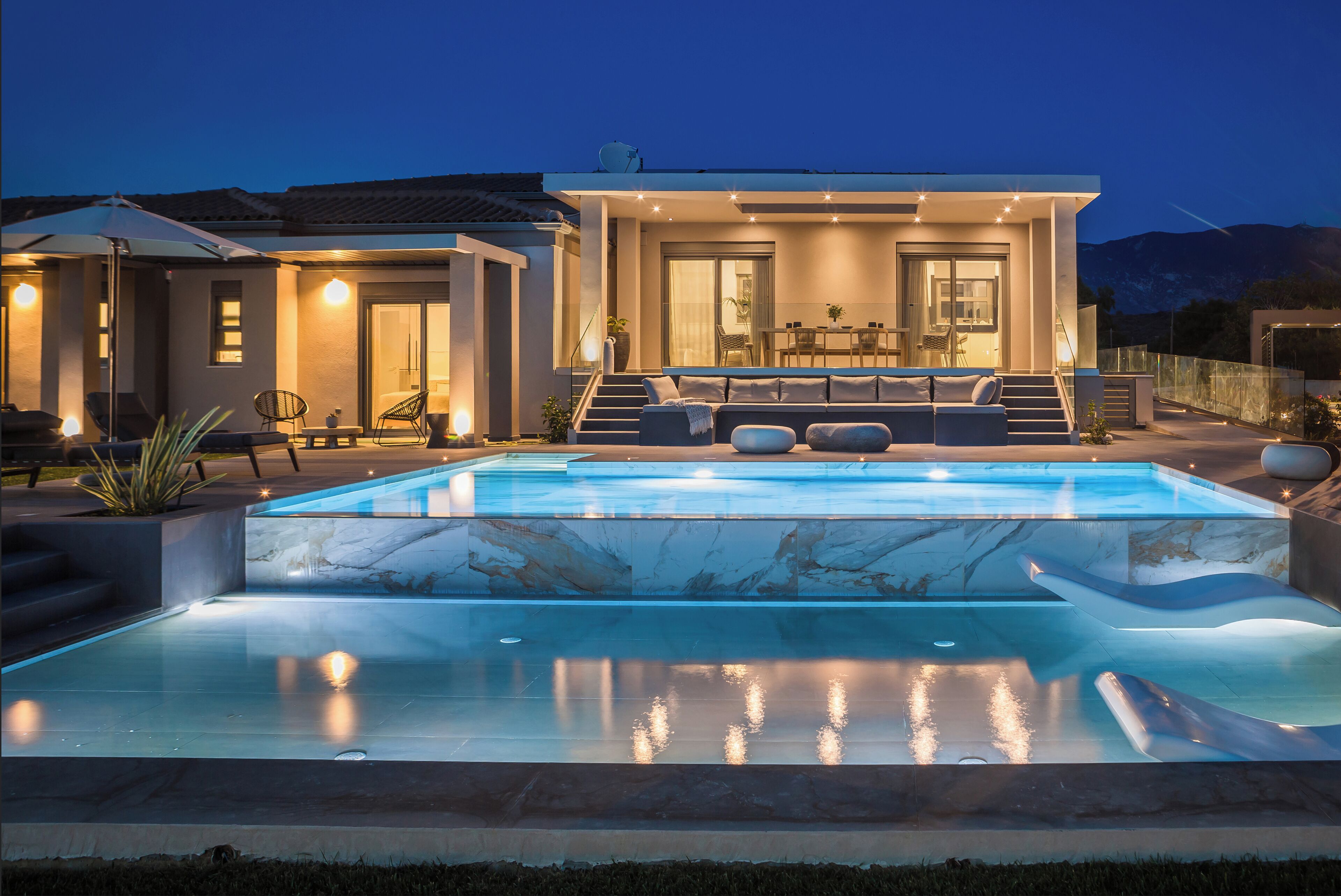 Una casa moderna con piscina, zona de estar exterior y comedor.